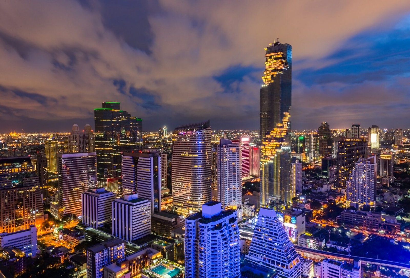 Bangkok skyline at night, towers lit gold against a dusk sky
