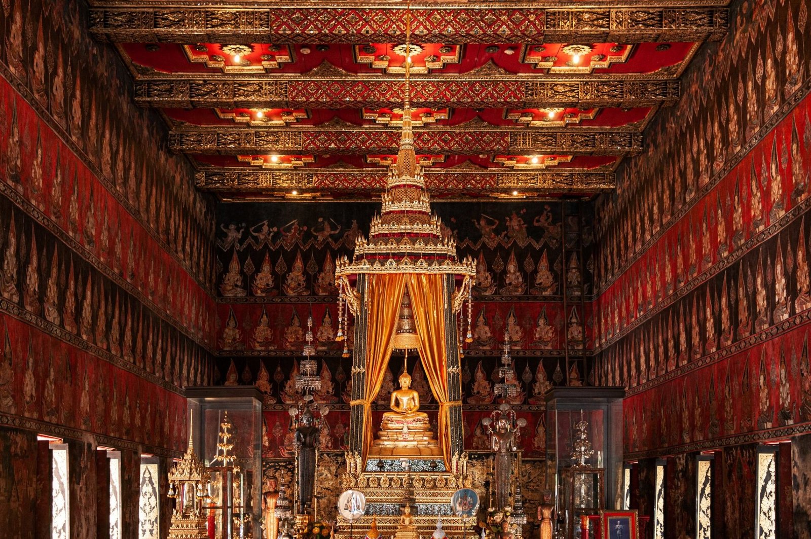 Ornate temple interior with golden Buddha beneath a multi-tiered canopy